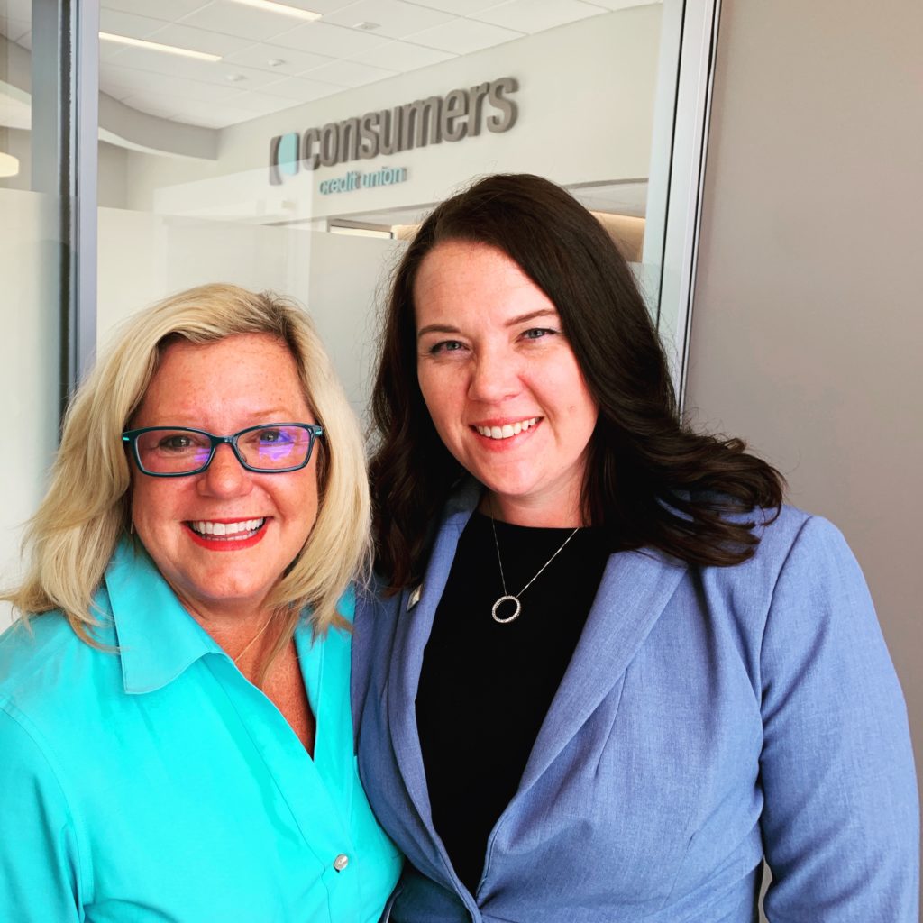 two women stand together smiling