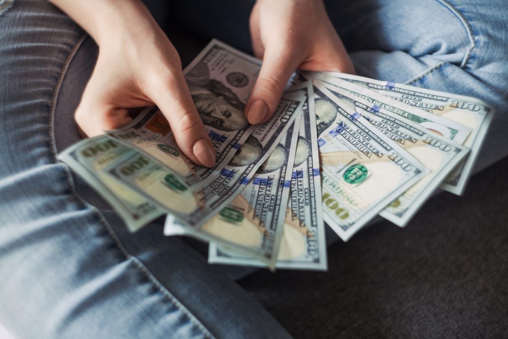 Person holding a fan of money in their hands