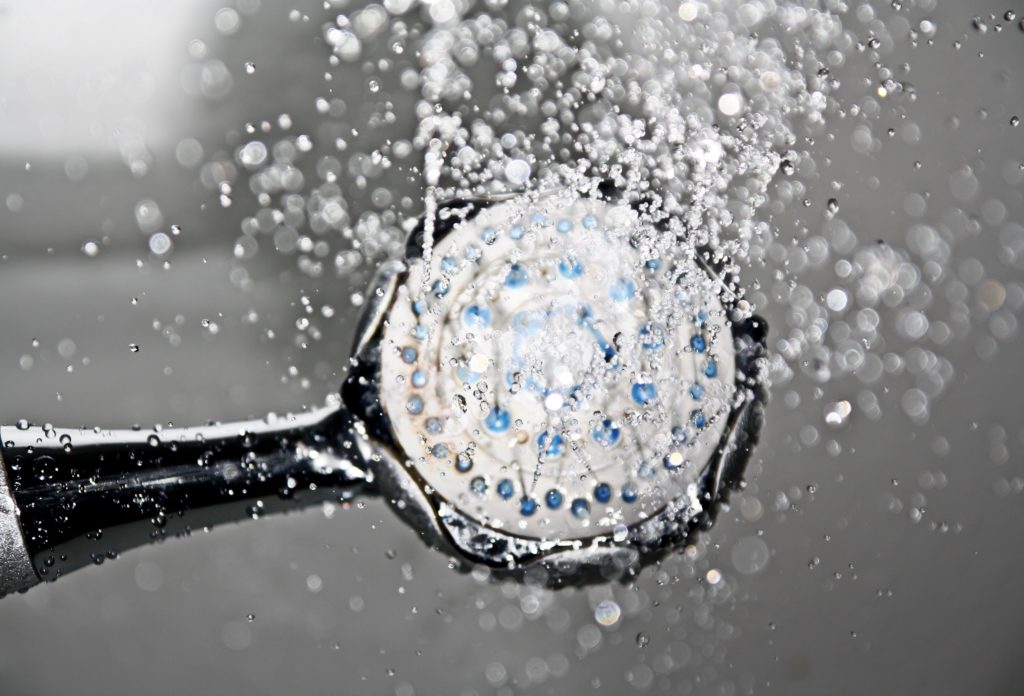 Black shower head switched on with water coming out