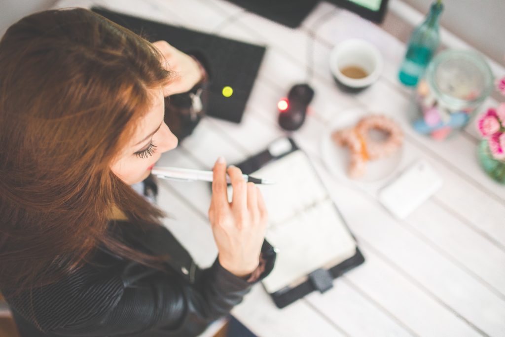 Young woman thinking with pen while sitting at a desk